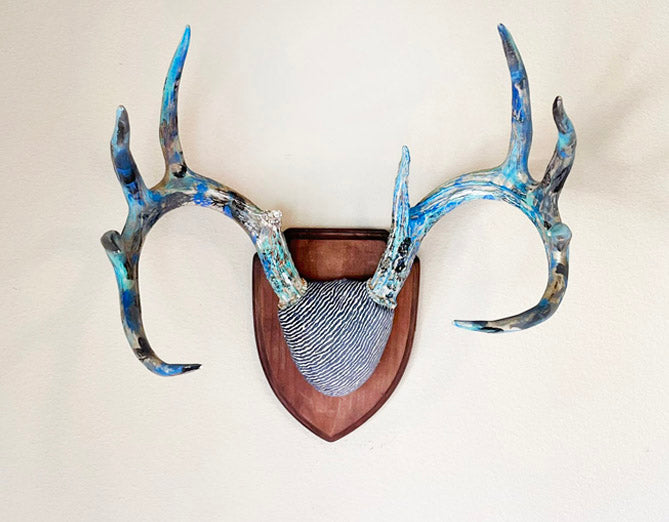 image of large hand painted whitetail deer antlers mounted on wooden plaque with blue denim colored fabric