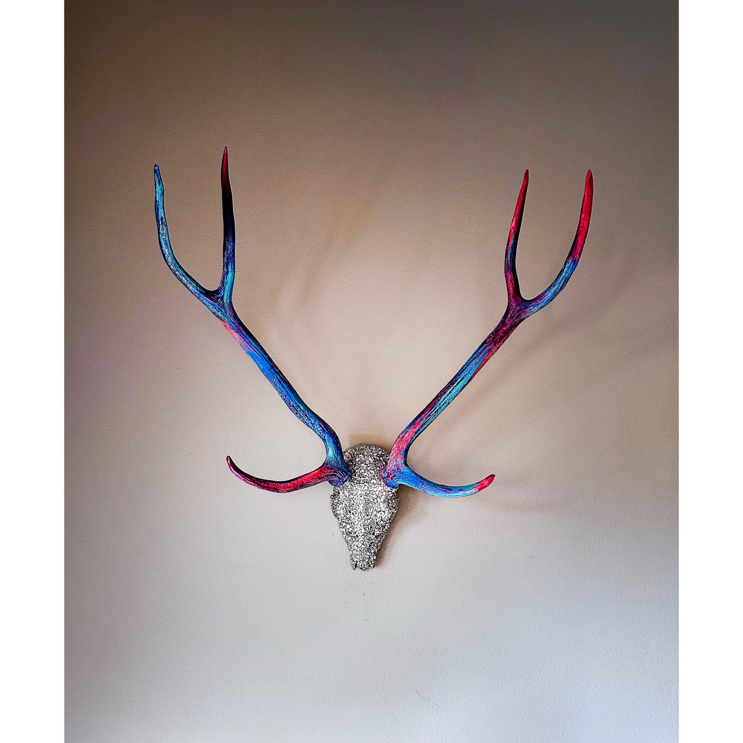 Decorative deer head with colorful antlers on a plain background
